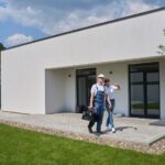 Woman telling to male worker on terrace of new modern townhouse before repair