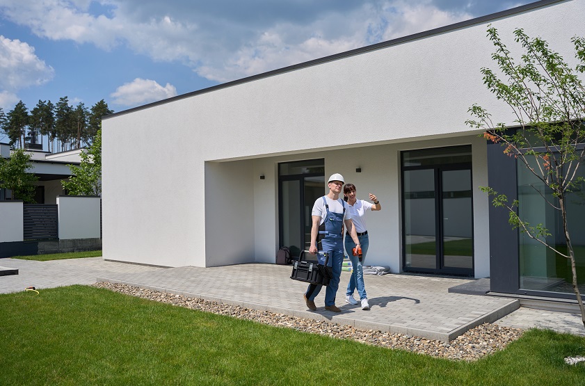 Woman telling to male worker on terrace of new modern townhouse before repair